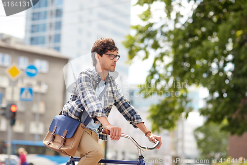 Image of young hipster man with bag riding fixed gear bike