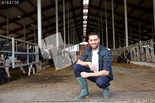 Image of man or farmer with cows in cowshed on dairy farm