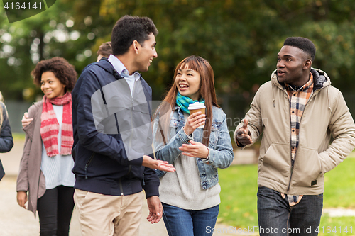 Image of happy friends walking along autumn park