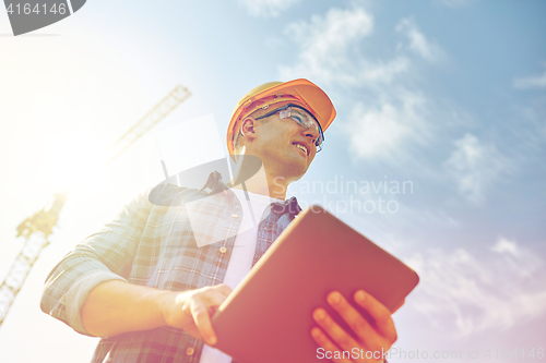 Image of builder in hardhat with tablet pc at construction