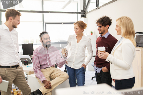 Image of happy business team drinking coffee at office