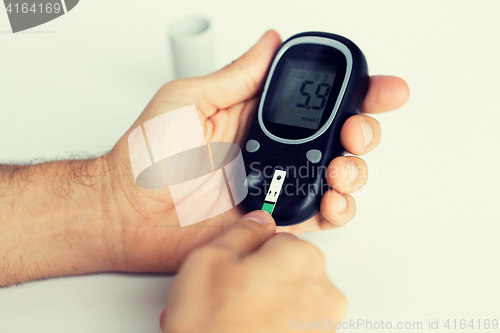 Image of close up of man checking blood sugar by glucometer