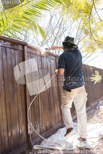 Image of Professional Painter Spraying Yard Fence with Stain