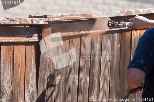 Image of Professional Painter Spraying Yard Fence with Stain