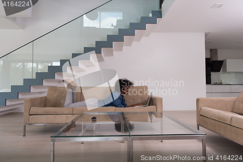 Image of African American woman using laptop on sofa