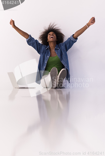Image of african american woman sitting on floor with laptop