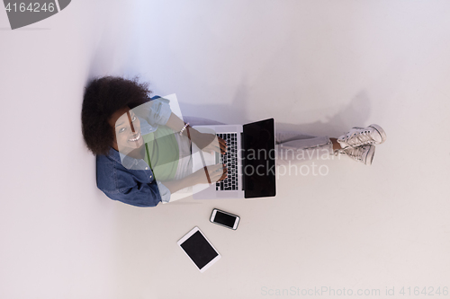 Image of african american woman sitting on floor with laptop top view