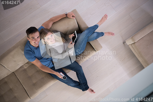 Image of youg couple in living room with tablet top view