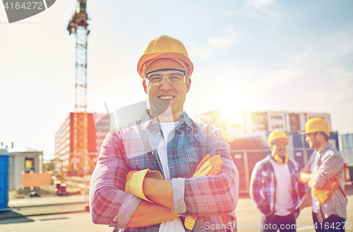 Image of group of smiling builders in hardhats outdoors