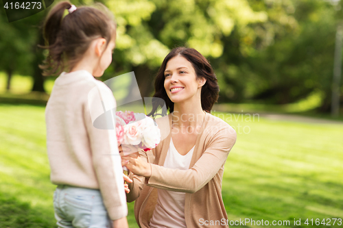 Image of girl giving with flowers to mother in summer park