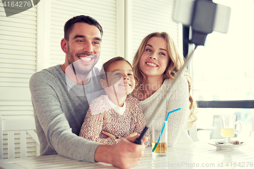 Image of happy family taking selfie at restaurant