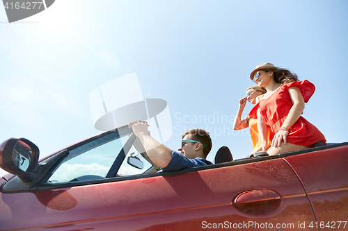 Image of happy friends driving in cabriolet car outdoors