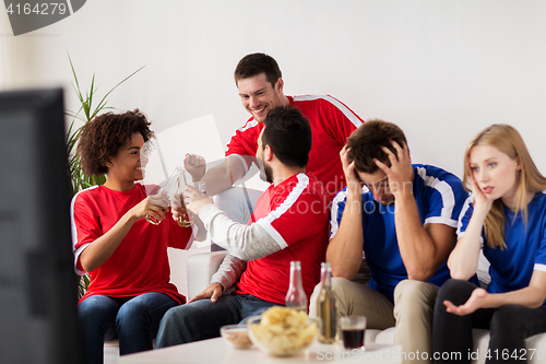 Image of friends or football fans watching soccer at home