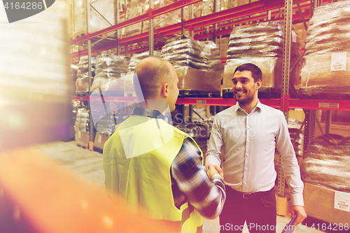 Image of worker and businessmen with clipboard at warehouse