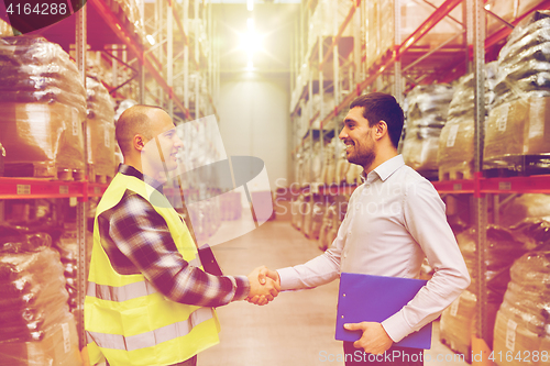 Image of worker and businessmen with clipboard at warehouse