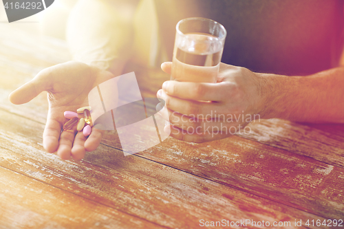 Image of close up of male hands holding pills and water