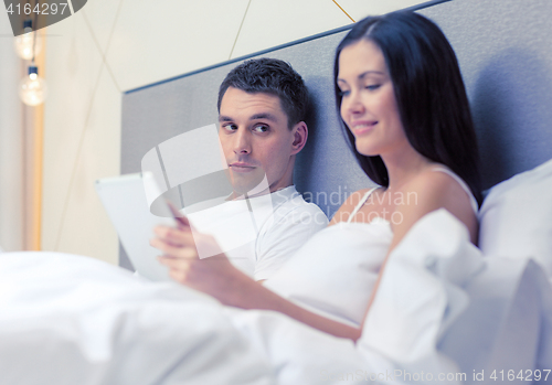 Image of smiling couple in bed with tablet pc computers