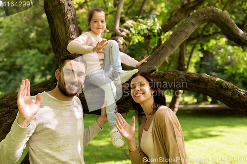 Image of happy family in summer park waving hands