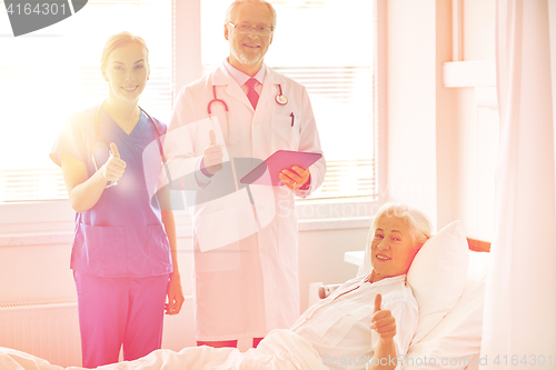 Image of doctor and nurse visiting senior woman at hospital