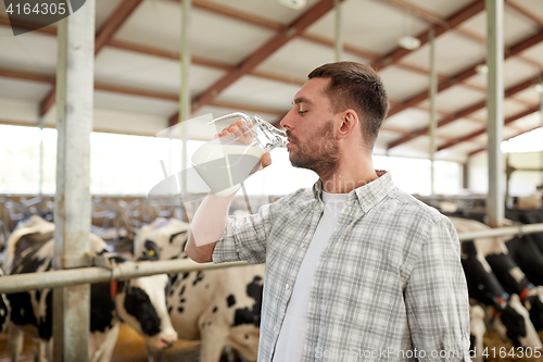 Image of man or farmer drinking cows milk on dairy farm