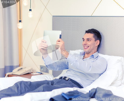 Image of happy businesswoman with tablet pc in hotel room