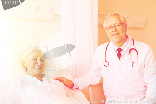 Image of doctor visiting senior woman at hospital ward