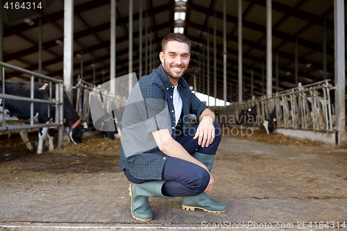 Image of man or farmer with cows in cowshed on dairy farm