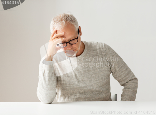 Image of sad senior man sitting at table