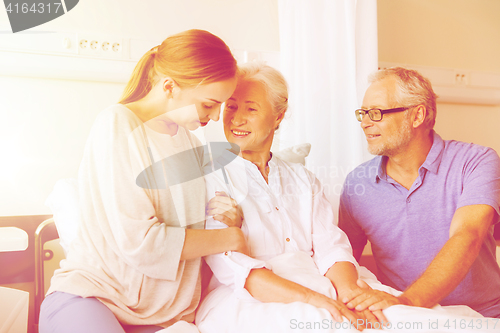 Image of happy family visiting senior woman at hospital