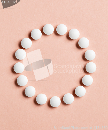 Image of white pills on pink background