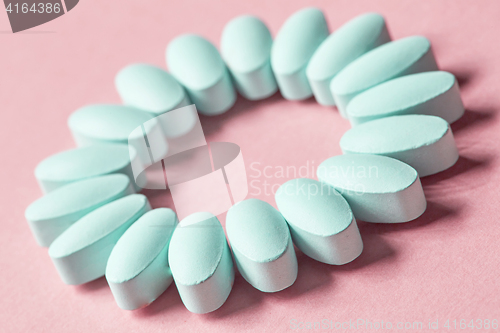 Image of blue pills on pink background