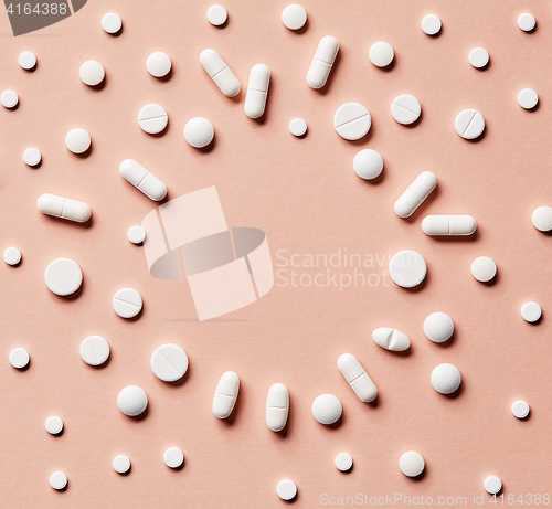 Image of white pills on pink background