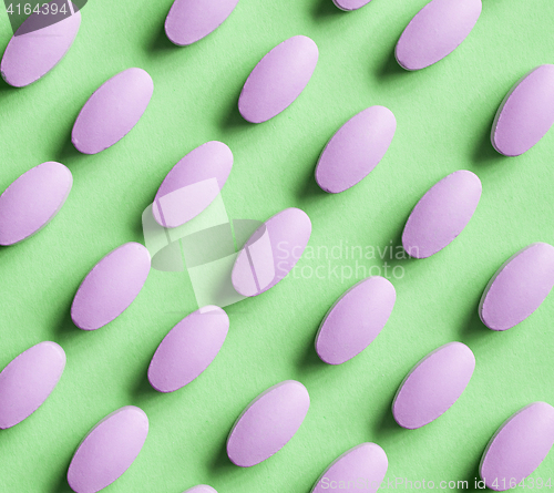 Image of purple pills on green background