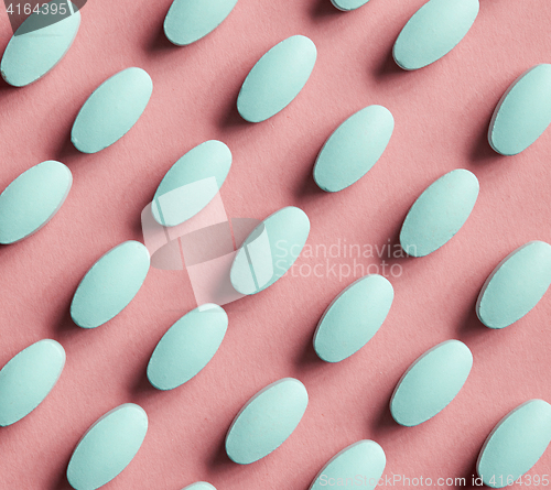 Image of green pills on pink background