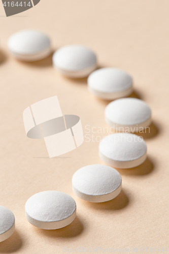 Image of white pills on beige background