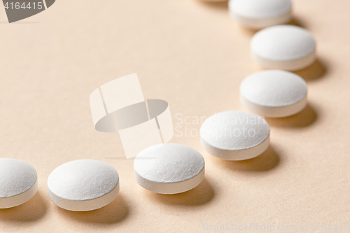 Image of white pills on beige background