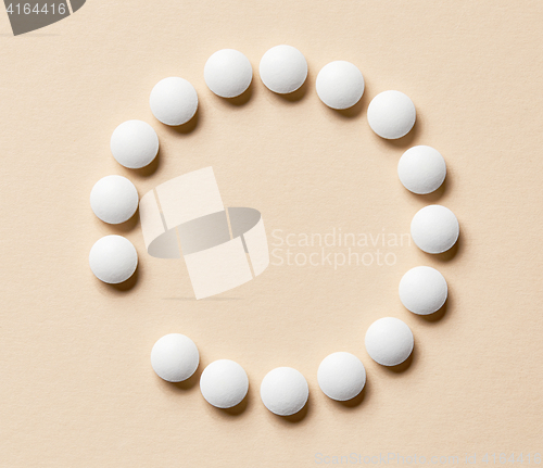 Image of white pills on beige background