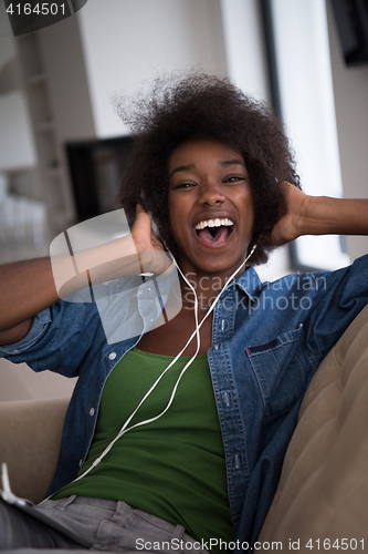 Image of African american woman at home in chair with tablet and head pho