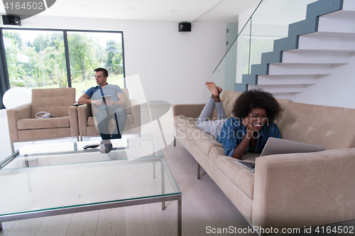 Image of young multiethnic couple relaxes in the living room