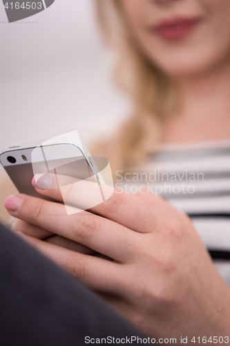 Image of woman sitting on sofa with mobile phone