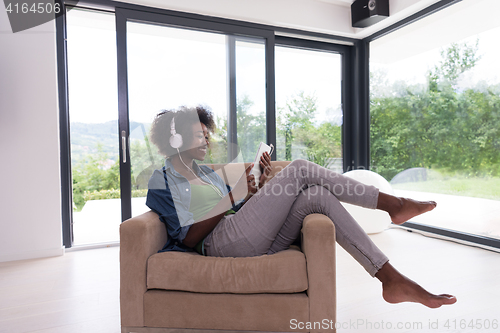 Image of African american woman at home in chair with tablet and head pho