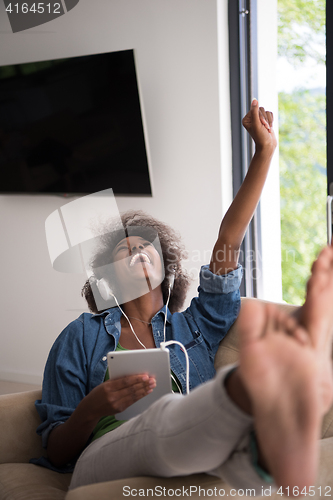 Image of African american woman at home in chair with tablet and head pho