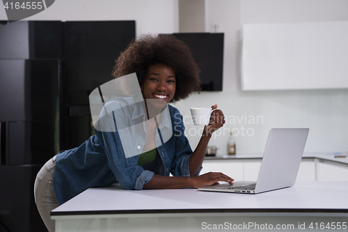 Image of smiling black woman in modern kitchen