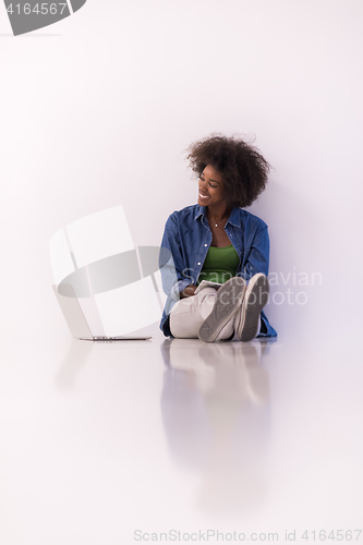 Image of african american woman sitting on floor with laptop