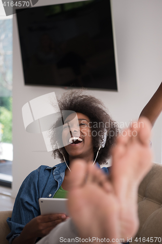 Image of African american woman at home in chair with tablet and head pho