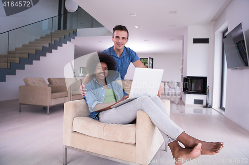 Image of multiethnic couple on an armchair with a laptop