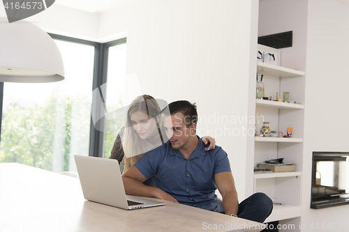 Image of couple using laptop at home