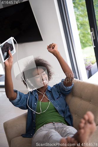 Image of African american woman at home in chair with tablet and head pho