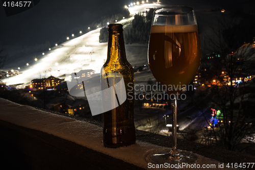 Image of Glass and bottle with craft beer on a balcony at skiing village