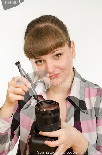 Image of Photographer cleans front of the lens on the camera, and looked into the frame